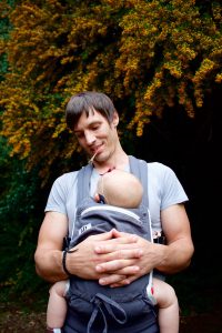 A man holding a baby in a carrier
