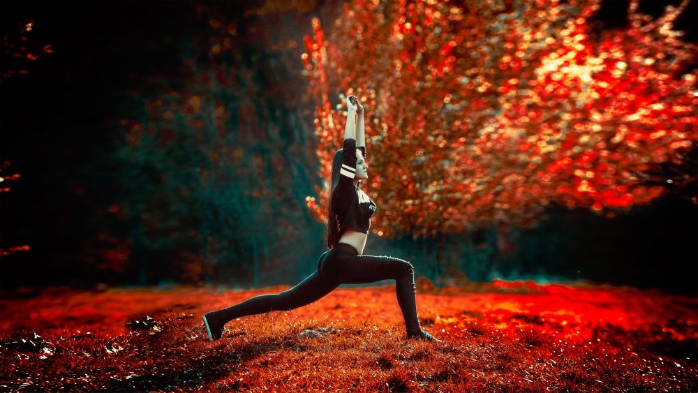 Woman doing yoga with bright red background of red trees